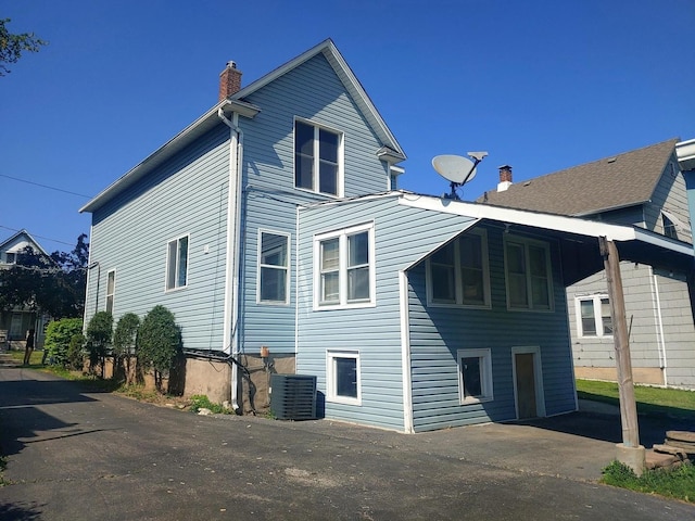 rear view of property with a chimney and cooling unit