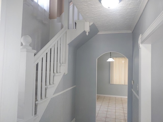 corridor with a textured ceiling, arched walkways, stairs, and light tile patterned flooring
