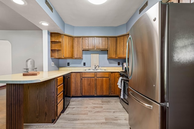 kitchen with stainless steel appliances, brown cabinetry, a sink, open shelves, and light countertops