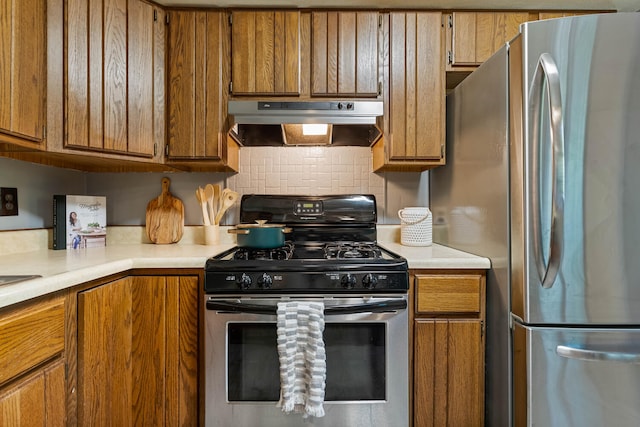 kitchen with appliances with stainless steel finishes, under cabinet range hood, brown cabinets, and light countertops