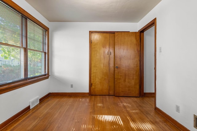 unfurnished bedroom featuring baseboards, hardwood / wood-style floors, and a closet