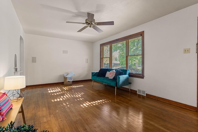 unfurnished room with wood finished floors, arched walkways, baseboards, and a ceiling fan