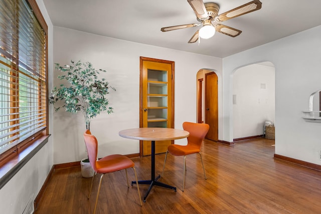 dining area with arched walkways, wood finished floors, baseboards, and ceiling fan