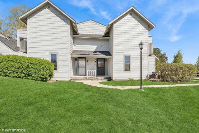 rear view of property featuring a yard and a shingled roof