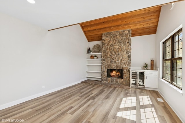 unfurnished living room featuring vaulted ceiling, light wood finished floors, a fireplace, baseboards, and wood ceiling