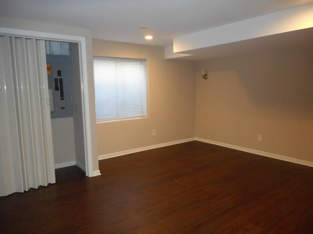 unfurnished room featuring electric panel, dark wood-type flooring, baseboards, and recessed lighting