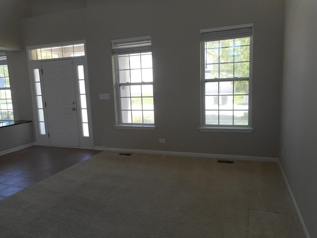 tiled entryway with healthy amount of natural light, baseboards, and carpet floors