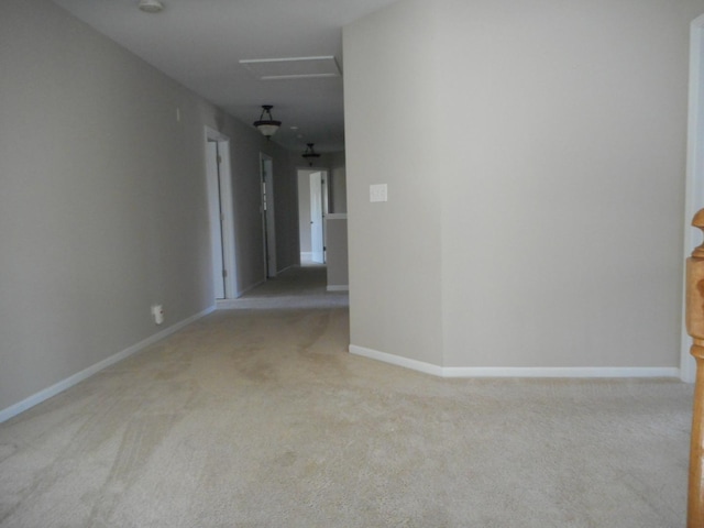 unfurnished room featuring carpet, baseboards, and attic access