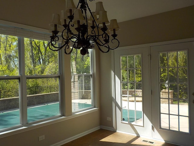 doorway to outside with a chandelier, baseboards, and tile patterned flooring