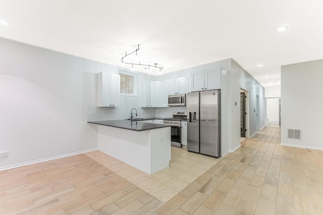 1107 S Independence Blvd Unit 1, Chicago, IL 60624 - kitchen with appliances with stainless steel finishes, dark countertops, a peninsula, backsplash, and light wood-style floors