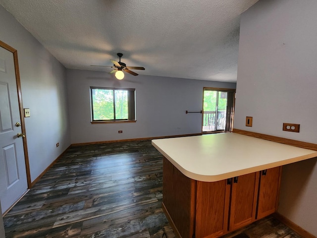 kitchen featuring a peninsula, a textured ceiling, dark wood finished floors, ceiling fan, and open floor plan
