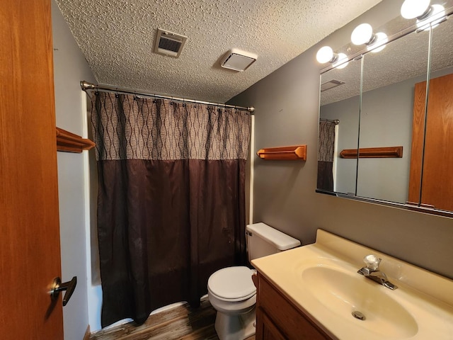 bathroom with wood finished floors, vanity, a textured ceiling, a shower with shower curtain, and toilet