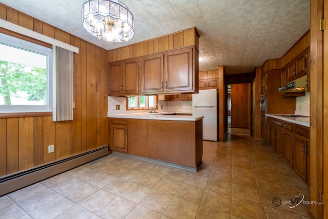 3760 Business 20th Rd, Freeport, IL 61032 - kitchen with freestanding refrigerator, a baseboard heating unit, brown cabinets, a peninsula, and wood walls