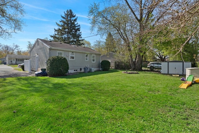 view of green lawn featuring a storage unit and an outbuilding