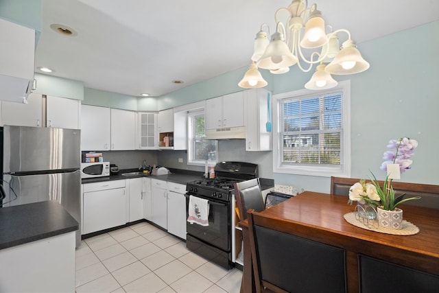 kitchen featuring black range with gas cooktop, under cabinet range hood, white microwave, dark countertops, and freestanding refrigerator