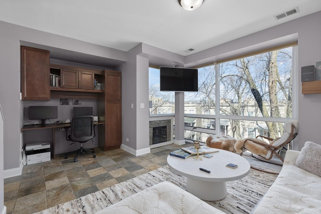 living area featuring stone tile floors, baseboards, and a fireplace