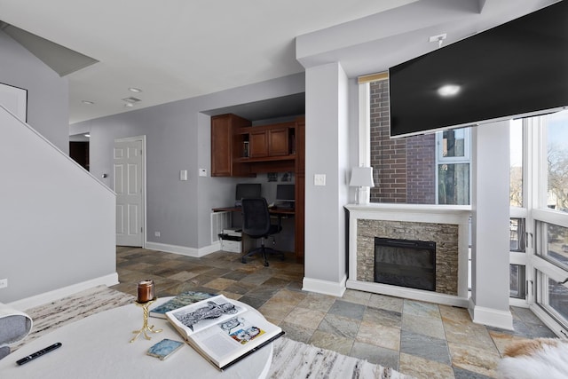 living room with stone tile flooring, baseboards, and a fireplace