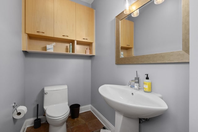 bathroom featuring baseboards, toilet, and a sink
