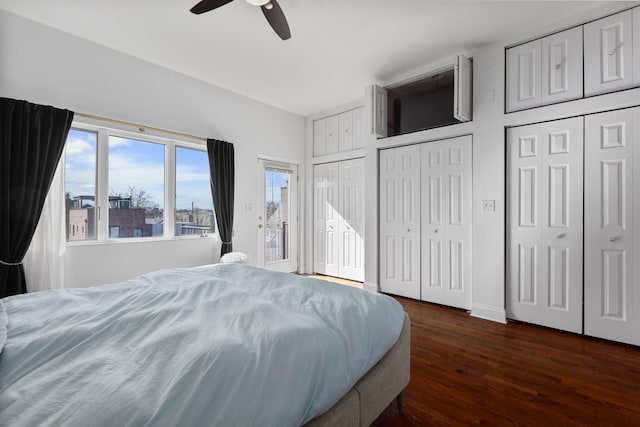 bedroom with two closets, dark wood-style floors, and ceiling fan