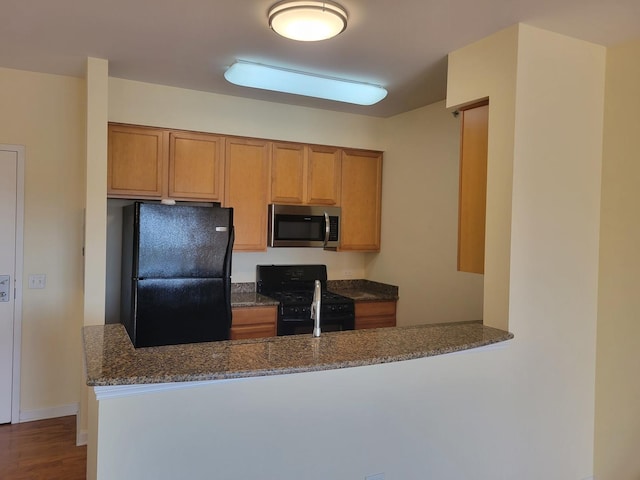 50 S Grove Ave Unit 510, Elgin, IL 60120 - kitchen with black appliances, dark stone counters, a peninsula, brown cabinetry, and dark wood-type flooring
