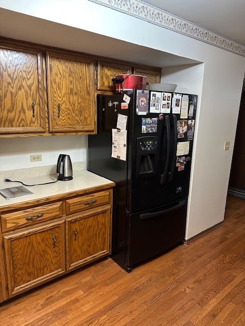 3806 Juniper Ave, Joliet, IL 60431 - kitchen featuring black fridge with ice dispenser, brown cabinetry, wood finished floors, and light countertops