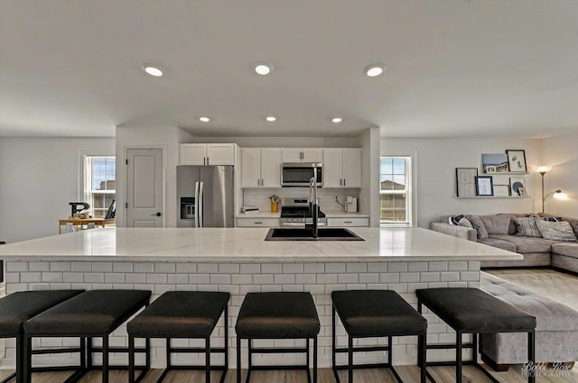 2451 Alison Ave, Pingree Grove, IL 60140 - kitchen with appliances with stainless steel finishes, a sink, white cabinets, decorative backsplash, and a breakfast bar