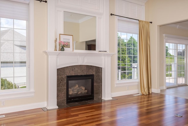 unfurnished living room with wood finished floors, baseboards, a fireplace, and ornamental molding