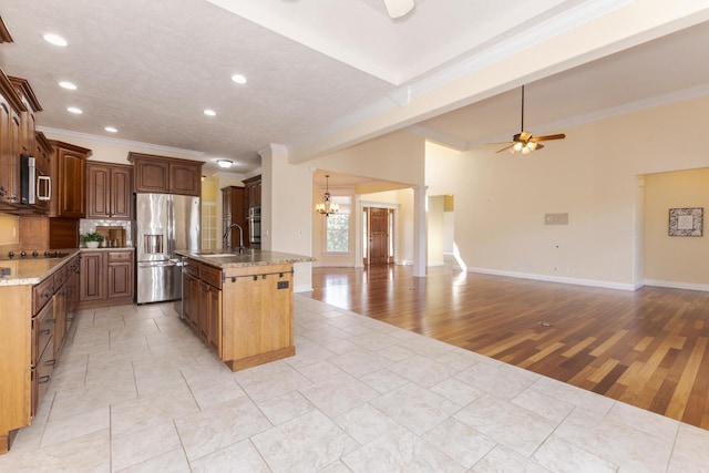kitchen featuring stainless steel appliances, a chandelier, a ceiling fan, open floor plan, and ornamental molding