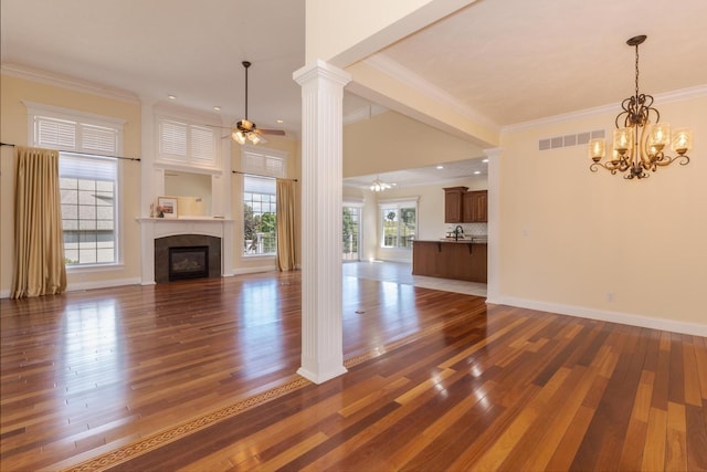 unfurnished living room with crown molding, plenty of natural light, a chandelier, and a ceiling fan