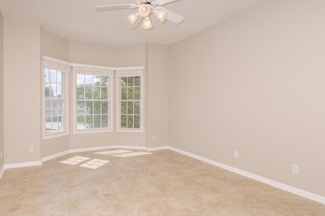 spare room with a ceiling fan and baseboards
