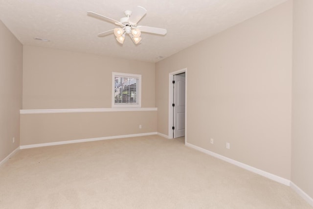 spare room with light carpet, baseboards, and a ceiling fan
