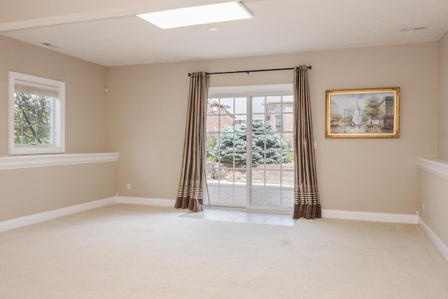 spare room featuring light colored carpet, healthy amount of natural light, and baseboards