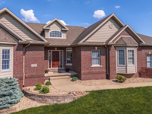 view of front facade with brick siding and roof with shingles
