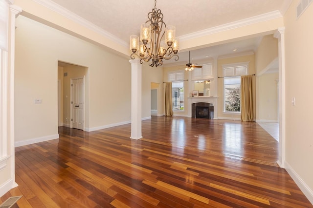 unfurnished living room featuring hardwood / wood-style flooring, ceiling fan, a chandelier, ornamental molding, and a tiled fireplace