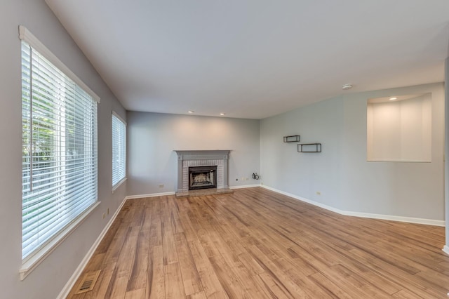unfurnished living room with light wood-type flooring, a brick fireplace, recessed lighting, and baseboards