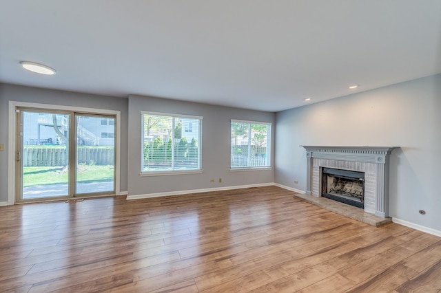 unfurnished living room featuring a fireplace, wood finished floors, baseboards, and recessed lighting
