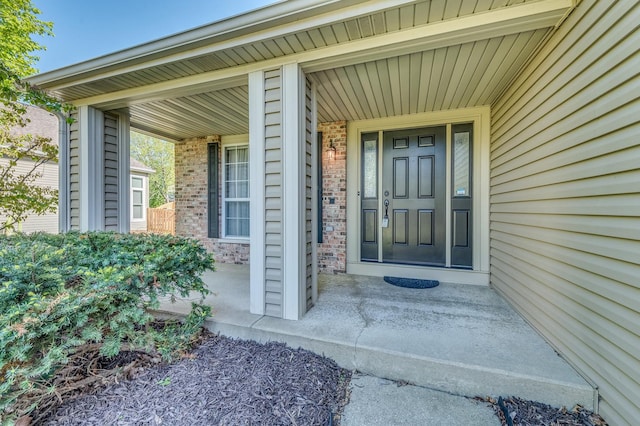 doorway to property with brick siding and covered porch