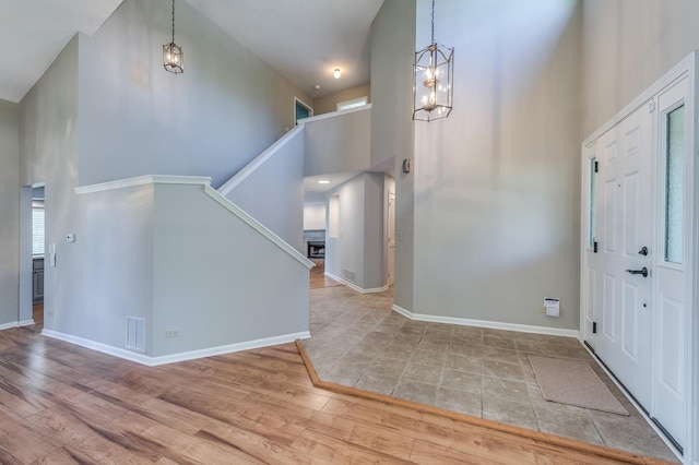 foyer entrance with a towering ceiling, stairway, wood finished floors, baseboards, and a chandelier