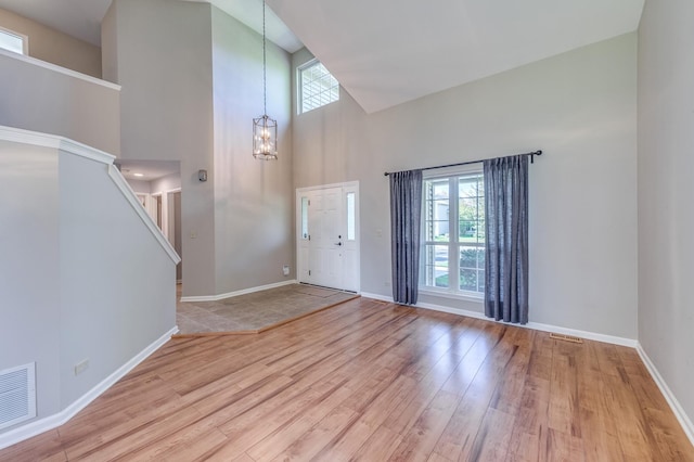 foyer with high vaulted ceiling, wood finished floors, a chandelier, baseboards, and stairs