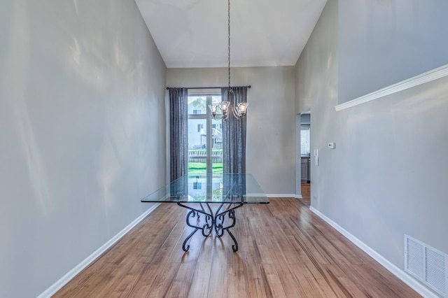 unfurnished dining area with a chandelier, baseboards, and wood finished floors