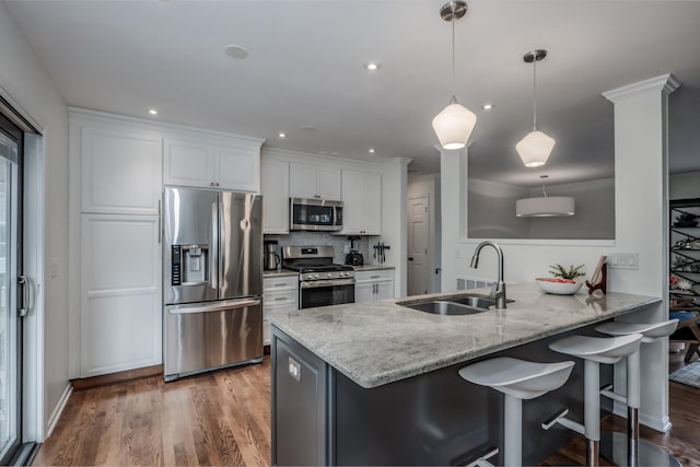 kitchen with appliances with stainless steel finishes, a sink, white cabinetry, a peninsula, and decorative backsplash