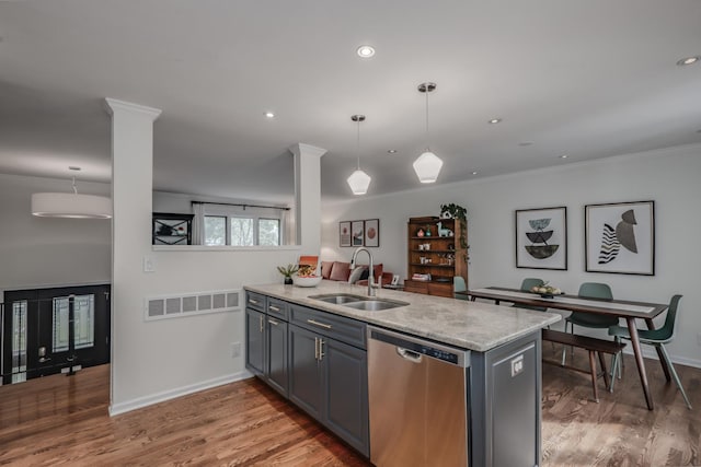 kitchen with a sink, stainless steel dishwasher, a peninsula, light stone countertops, and light wood-style flooring