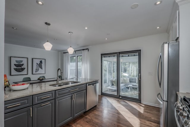 kitchen with stainless steel appliances, a sink, plenty of natural light, light stone countertops, and recessed lighting