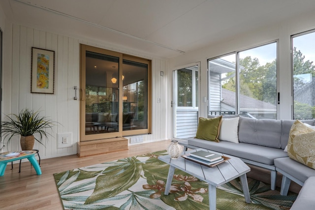 sunroom with plenty of natural light, wood finished floors, and a wooden deck
