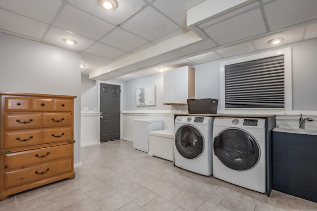 clothes washing area with washer and dryer, cabinet space, and light tile patterned flooring