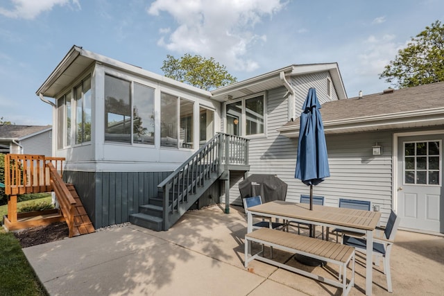 rear view of property featuring a sunroom, stairway, a patio area, and outdoor dining space