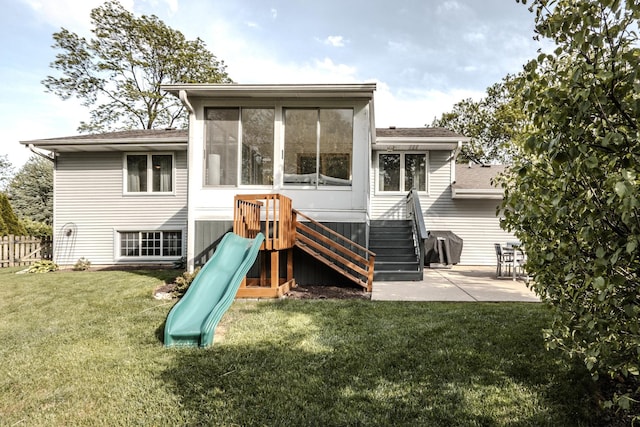 rear view of property featuring a playground, a patio, and a sunroom