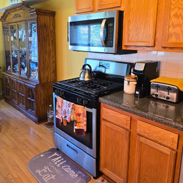 760 Mendocino Ct Unit 5, University Park, IL 60484 - kitchen with appliances with stainless steel finishes, decorative backsplash, light wood-style floors, and dark stone counters