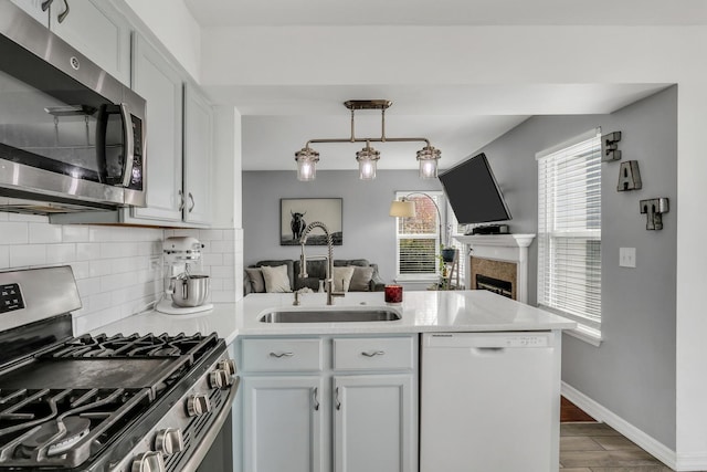 646 E Weston Ct, Round Lake Beach, IL 60073 - kitchen featuring appliances with stainless steel finishes, a peninsula, a sink, decorative backsplash, and light countertops