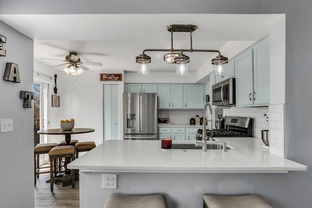 646 E Weston Ct, Round Lake Beach, IL 60073 - kitchen featuring appliances with stainless steel finishes, a peninsula, decorative backsplash, and blue cabinetry